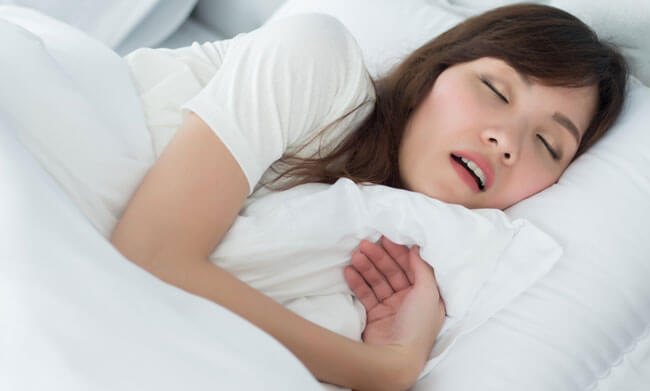  woman snoring while sleeping on bed in bedroom
